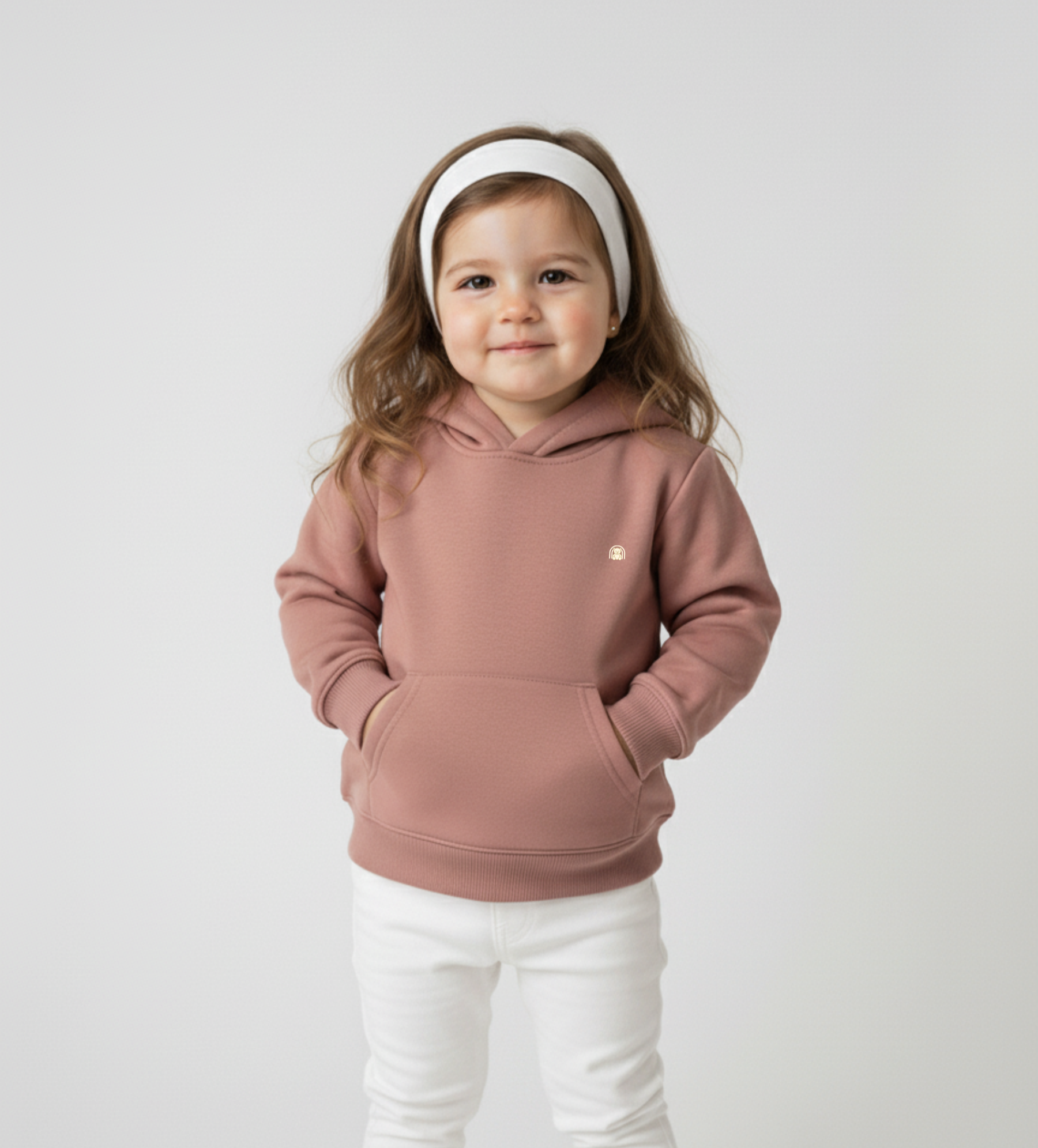 Child wearing a pink hoodie and white pants on a plain background